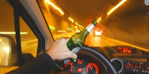 Ręka trzymająca butelkę piwa za kierownicą. Widok z wnętrza samochodu jadącego nocą. Stan nietrzeźwości, ile promili?