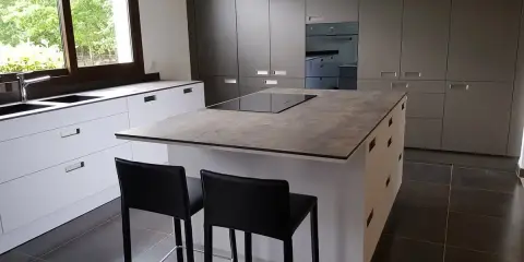 Cuisine moderne avec îlot central. On peut facilement faire le tour de cet îlot central pour accéder aux plans de travail et aux tabourets.