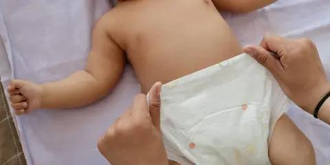 Rączki dziecka leżą na pieluszce, która jest zmieniana. Uważaj na grzybicę pieluszkową.