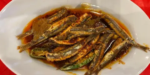 Piatto di alici marinate, un classico dei piatti tipici calabresi pesce, condite con olio, peperoncino e aromi.