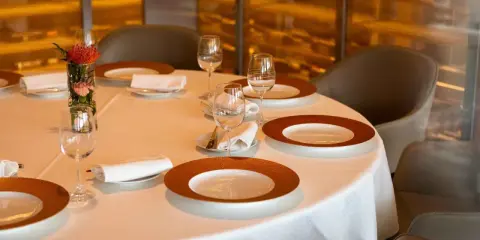 Dressage table gastronomique élégant avec vaisselle raffinée, verres à vin et une petite composition florale.