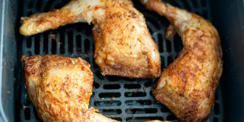 Muslos de pollo dorados y jugosos en la freidora de aire, listos para disfrutar.