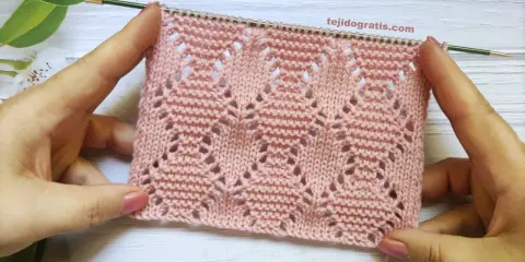 Muestra de tejido rosa con rombos a dos agujas patrones calados, ideal para prendas delicadas.