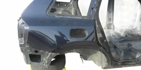 Tylna część nadwozia Volvo XC90 w kolorze granatowym, bez szyb i wnętrza, na żółtym wózku.