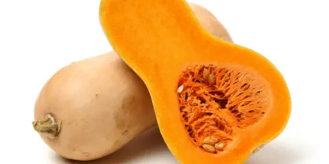 En hel och en halv butternutpumpa, med sitt orangea, fröfyllda inre. En riktigt nyttig och mångsidig grönsak.