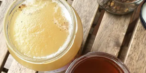 Dwa słoiki miodu, jasnego i ciemnego, na drewnianym stole. Jak sprawdzić czy miód jest prawdziwy?
