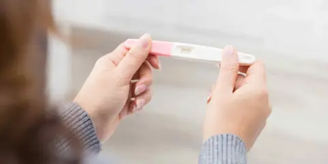 Kvinna håller graviditetstest. Ett streck syns, vilket indikerar negativt resultat, trots att hon känner sig gravid i vecka 7.