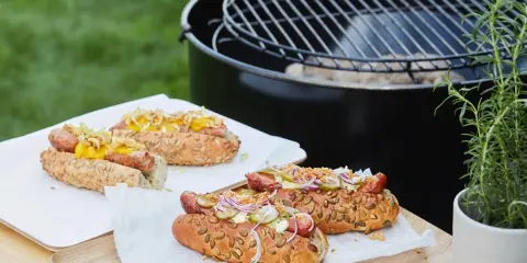 Délicieux hot dogs prêts pour un barbecue, avec des garnitures fraîches et un pain aux graines.