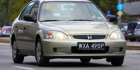 Złoty sedan Honda Civic z widocznym numerem rejestracyjnym WXA 490P. Brak tablicy rejestracyjnej z przodu.