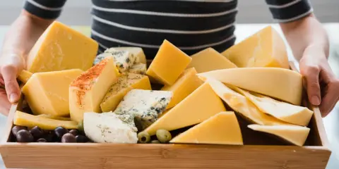 Taca pełna serów, w tym kawałki z niebieską pleśnią i przyprawami, z oliwkami. Wygląda jak najzdrowszy ser żółty na świecie!