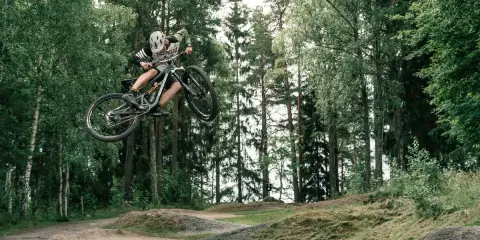 Mountainbike-åkare flyger genom luften i en skogspark nära Stockholm.