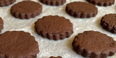 Deliziosi biscotti senza burro al cacao, con bordo ondulato, disposti su una teglia.