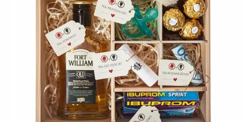 Drewniana skrzynka z zawartością: butelka whisky, smoczek, czekoladki, leki, pieniądze i losy. To idealny **niezbędnik małżeński co włożyć** na szczęście i przyszłość.