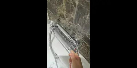 Dłoń reguluje uchwyt baterii termostatycznej, by uzyskać idealną temperaturę ciepłej wody.