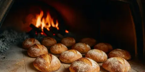 Des pains dorés attendent leur temps de cuisson du pain au four, avec des flammes vives en arrière-plan.