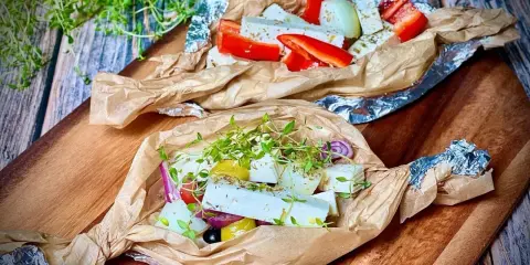 Zwei Päckchen mit Feta, Paprika, Zwiebeln und Kräutern warten darauf, gegrillt zu werden. Ein Genuss für den Gaumen!