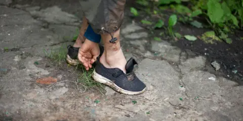 Schmutzige Turnschuhe auf dem Boden, die Person versucht, sie zu trocknen.