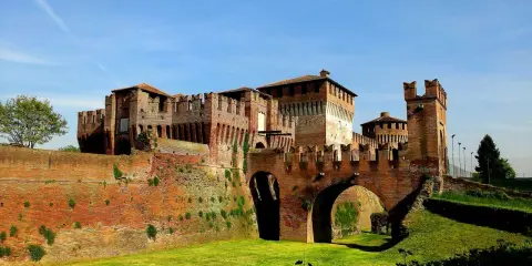 Castello Sforzesco, uno dei borghi belli vicino Cremona, con mura in mattoni rossi, ponti ad arco e fossato verde.