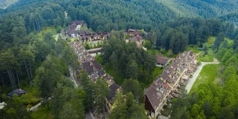 Villaggio Mancuso immerso nel verde, con case a schiera e palazzine circondate da fitti boschi di conifere.