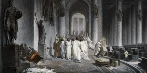 Die Ermordung Caesars: Senatoren mit erhobenen Dolchen umringen den gefallenen Diktator. Ein umgestürzter Stuhl und eine Leiche auf dem Boden zeugen vom brutalen Ende.