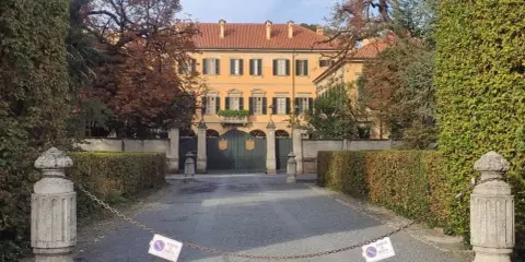 Ingresso di Villa San Martino ad Arcore, con cancello verde e alberi autunnali. Catena con cartelli di divieto di sosta blocca l'accesso.