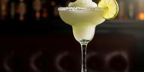 En frostig frozen margarita med saltkant och limeklyfta, perfekt för en varm dag.