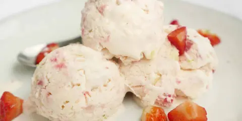 Tre kulor krämig jordgubbsglass med bitar av färska jordgubbar, en nyttig glass för varma sommardagar.