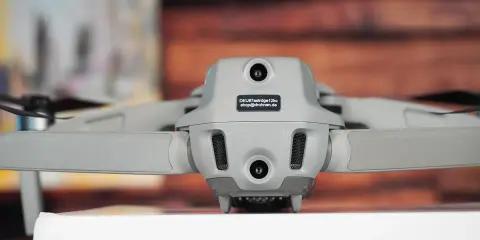 Graue Drohne Mavic Air 2 mit Kameras und Propellern. Auf dem Gehäuse ist ein Aufkleber mit der Kennung zur drohne registrieren.