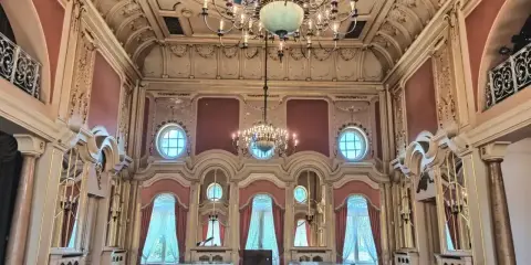 Wnętrze pałacu poznańskiego z bogatymi zdobieniami, dwoma żyrandolami i niebieskim sufitem.