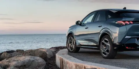 Nowy Peugeot 3008 hybryda na tle spokojnego morza i skalistego wybrzeża.