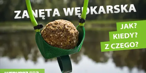 Kula zanęty wędkarskiej 5 kg w zielonej łopatce, gotowa do zarzucenia. W tle woda i drzewa.