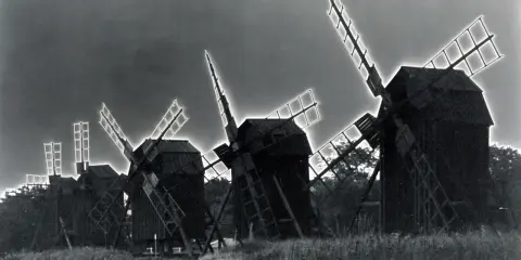 Mulini a vento in un campo, con un effetto di solarizzazione man ray che illumina le pale.