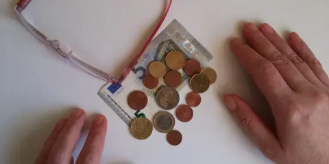 Manos sobre billetes y monedas, sugiriendo aportaciones a planes de pensiones IRPF.