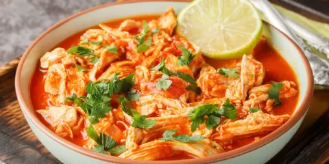 Pyszne danie z ugotowanych udek kurczaka w sosie pomidorowym, posypane natką pietruszki i udekorowane plasterkiem limonki. Idealne, gdy zastanawiasz się, co zrobić z ugotowanych udek kurczaka.