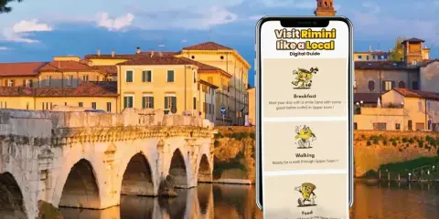 Guida digitale "Visit Rimini like a Local" con suggerimenti per colazione, passeggiate e cibo, sullo sfondo del Ponte di Tiberio.