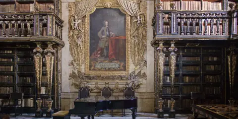 Prachtvolle Coimbra Bibliothek mit einem Flügel und einem Porträt.