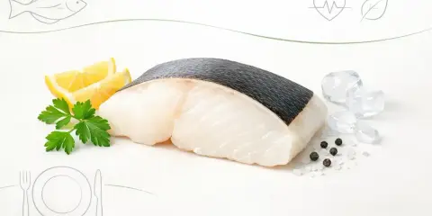 Świeży kawałek halibuta z cytryną i pietruszką. Czy halibut jest zdrowy? Tak, to ryba bogata w białko i kwasy omega-3.