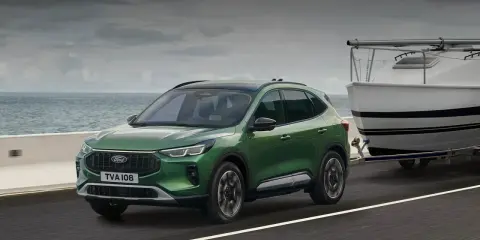 Zielony Ford Kuga z przyczepą i łodzią, idealny na wakacyjne wyjazdy. Sprawdź ford kuga cena!