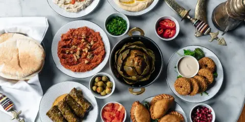 En generös dukning med libanesisk mat: hummus, baba ghanoush, falafel, dolmar, piroger och en hel kronärtskocka.