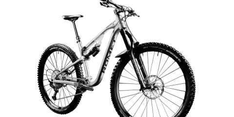 Srebrny rower górski (MTB) z pełnym zawieszeniem, szerokimi oponami Michelin Wild Enduro i amortyzatorem Rock Shox. Idealny na trudne trasy, nie crossowy.