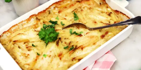 En krämig Janssons frestelse i en vit form, redo att serveras. Perfekt för ett julbord eller en mysig middag.