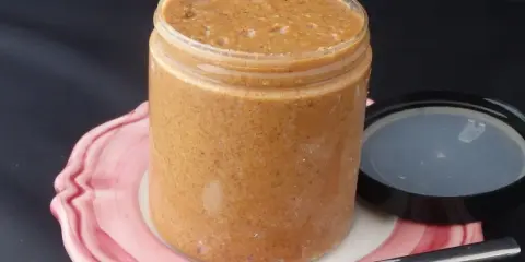 Un pot de praliné maison, onctueux et gourmand, prêt à être dégusté avec une cuillère.