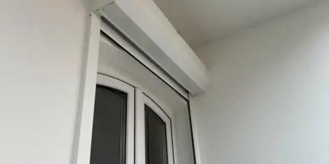 Un imposte blanc est installé au-dessus d'une porte-fenêtre blanche.