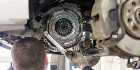 Mechanik dokonuje wymiany sprzęgła w Nissan Qashqai 1.6 benzyna. Widoczny jest mechanizm sprzęgła i narzędzia.
