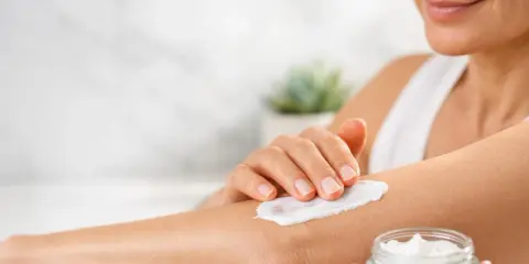 Donna applica crema idratante sul braccio per alleviare il prurito sine materia.
