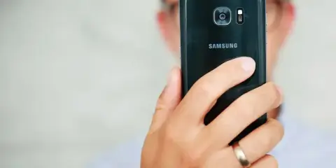 Osoba trzyma czarny telefon Samsung, pokazując tył z aparatem. Dowiedz się, jak poprawić jakość aparatu w telefonie Samsung, aby robić lepsze zdjęcia.