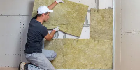Operaio posiziona pannelli isolanti per il cappotto casa. L'isolamento termico è fondamentale per il comfort abitativo.