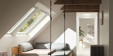 Aménagement comble 1m50 : un espace cosy avec balançoire, lit bas et vue sur la nature par les fenêtres de toit.