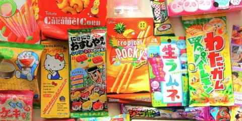 Un surtido vibrante de chuches famosas japonesas, incluyendo Pocky, Caramel Corn y dulces de Hello Kitty y Doraemon.