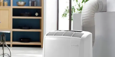 Climatiseur mobile blanc avec tuyau d'évacuation relié à une fenêtre.